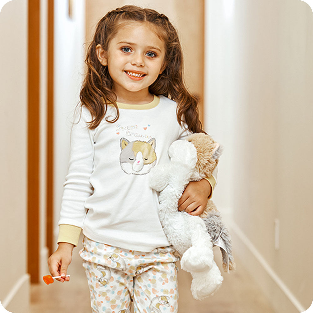 Image 102: girl holding calico cat warmies in cat pjs