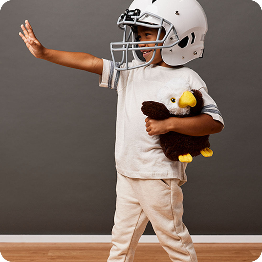 Image 104: boy in football gear holding an eagle stuffed animal